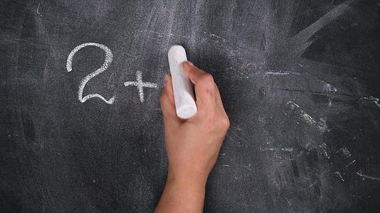 用白色粉笔在黑色粉板上写的数学示例用白色粉笔画在女人手上视频的预览图