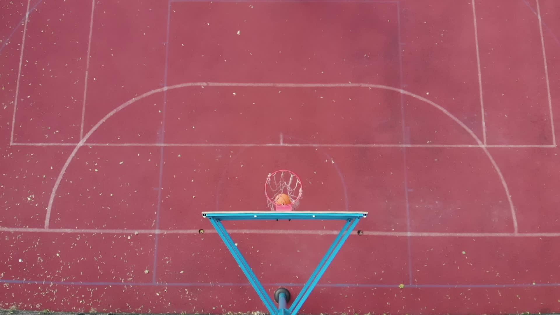 篮球篮板上方的高角橙色球干净地击中了篮筐并在户外球场上视频的预览图