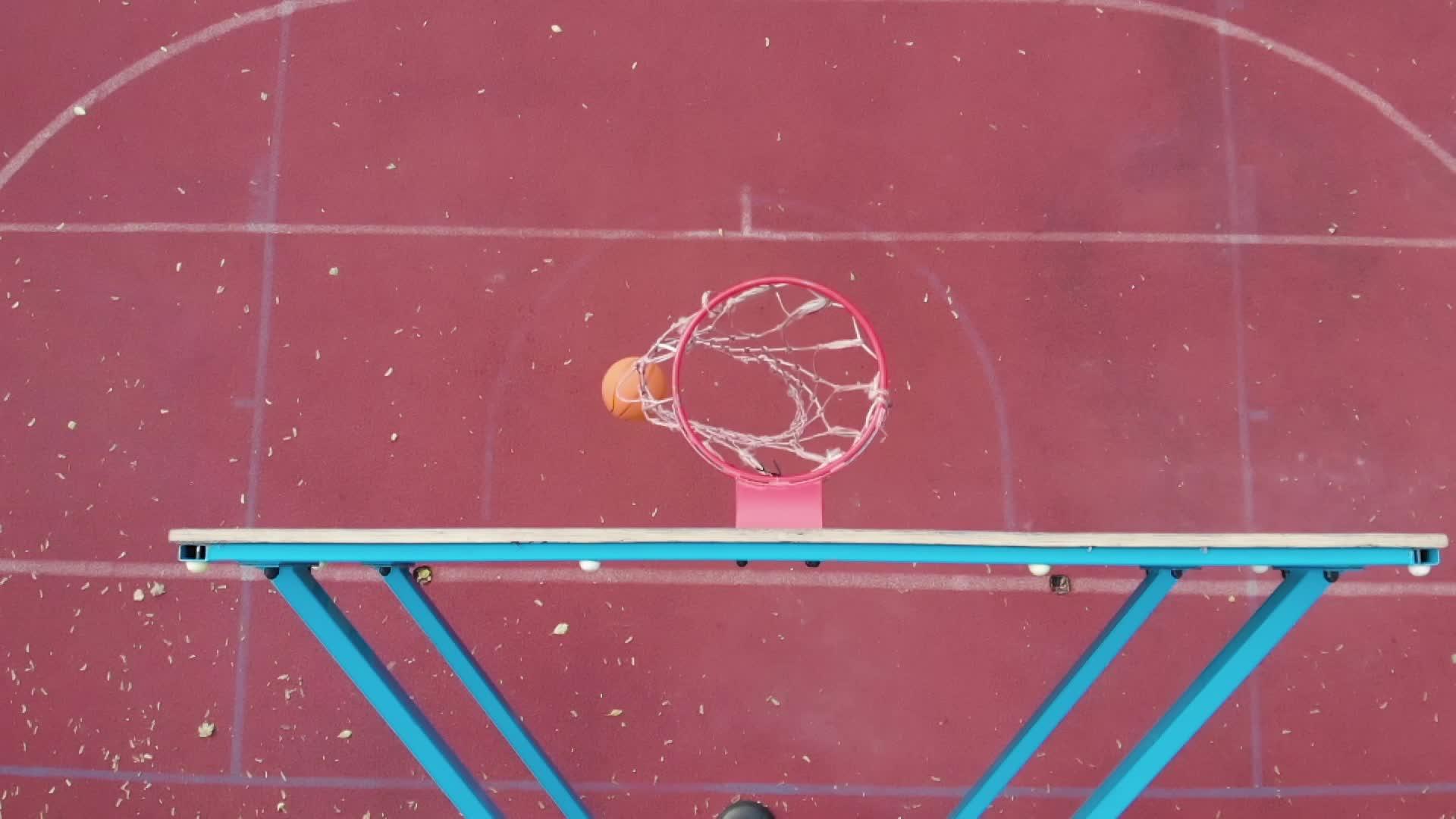 把橙色的篮球扔在篮板上方的顶角击中篮筐盖住树叶视频的预览图