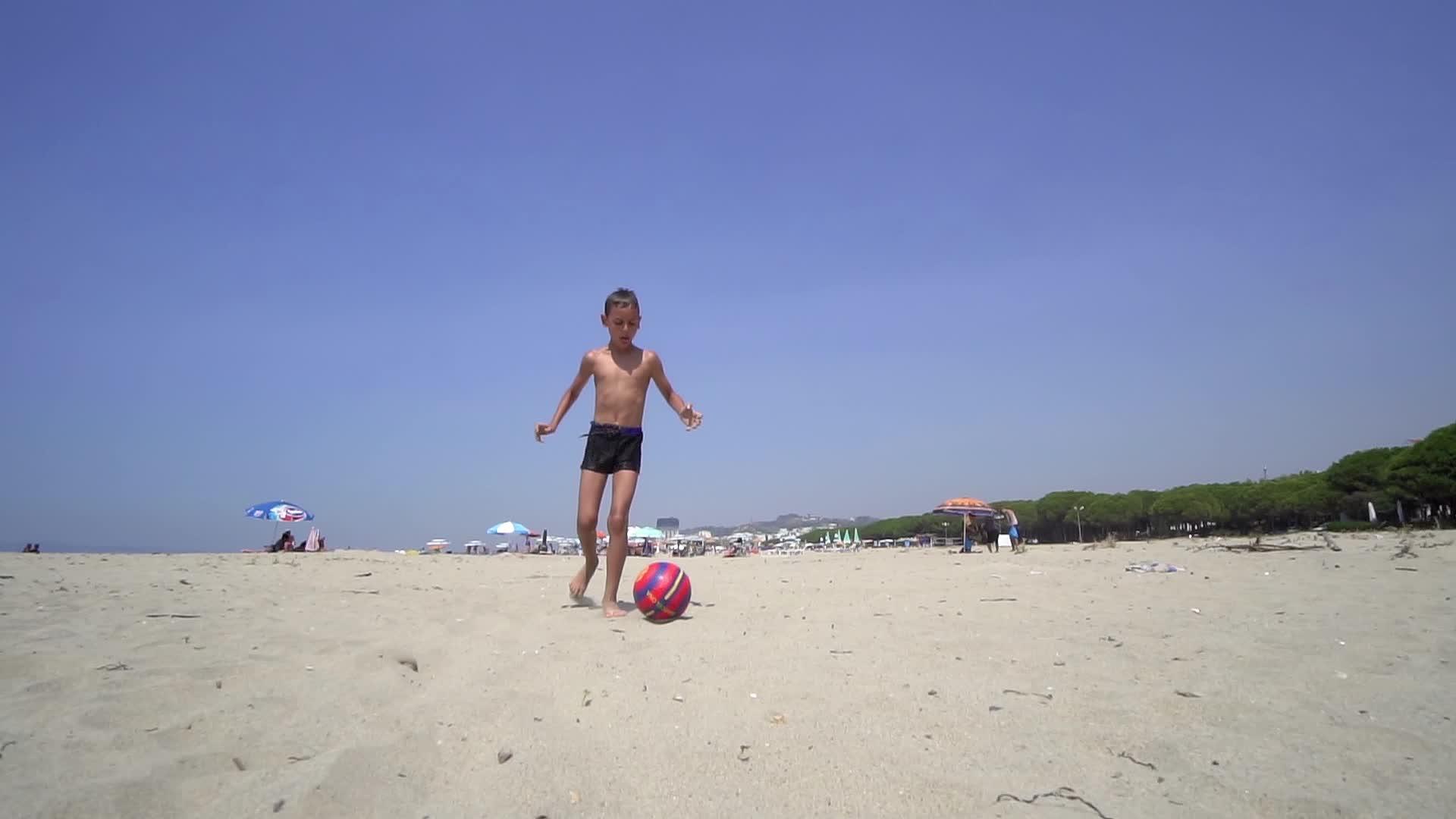 暑假期间在海滩上踢足球的男孩积极运动的概念视频的预览图