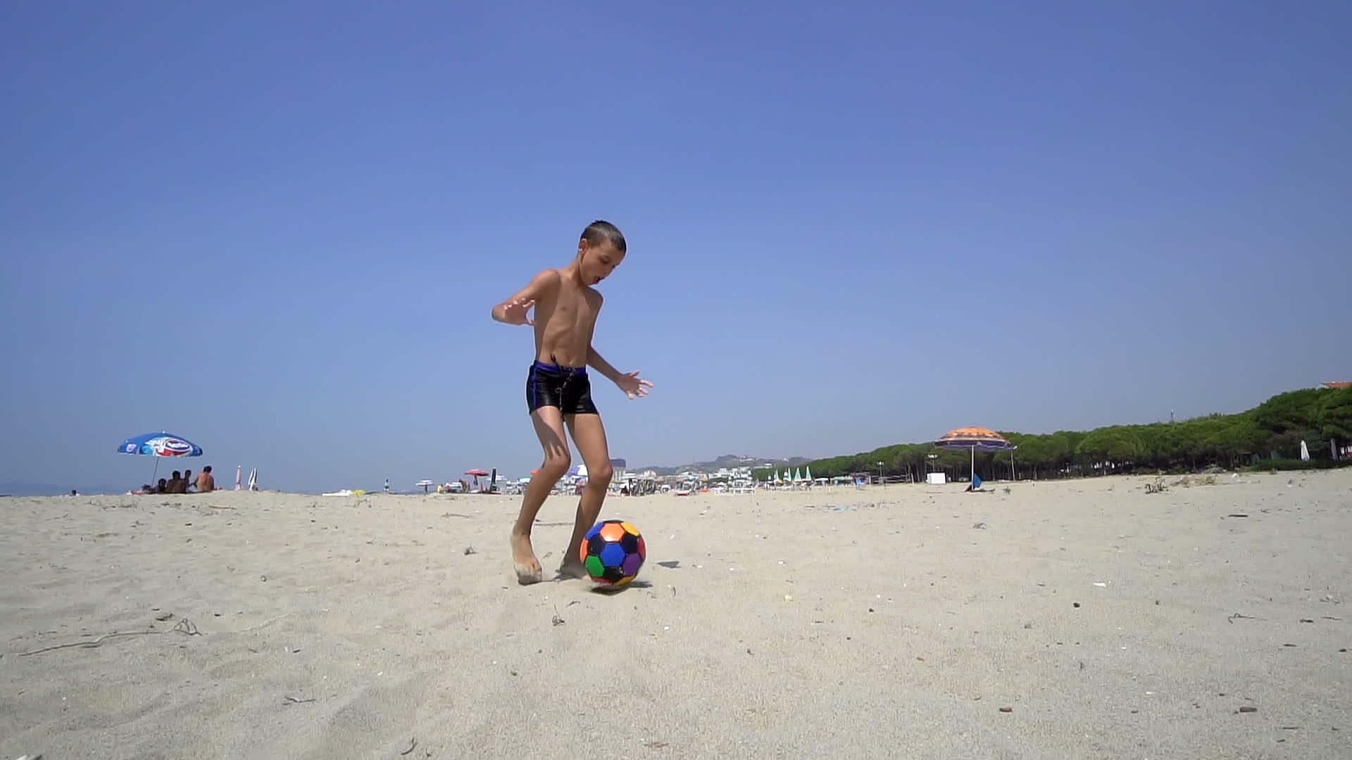 年轻男孩踢足球踢足球赤脚在沙滩上跑视频的预览图