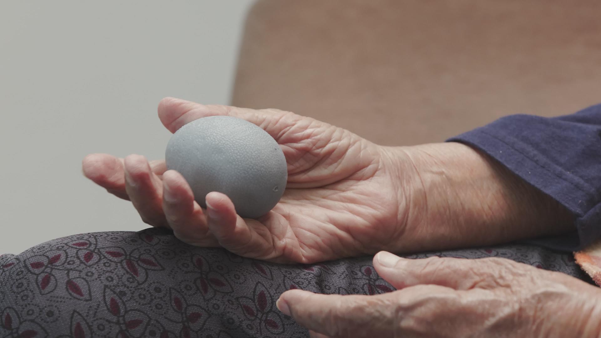 老年妇女用橡胶球锻炼手指、棕榈手和脚肌肉照顾者应小心视频的预览图