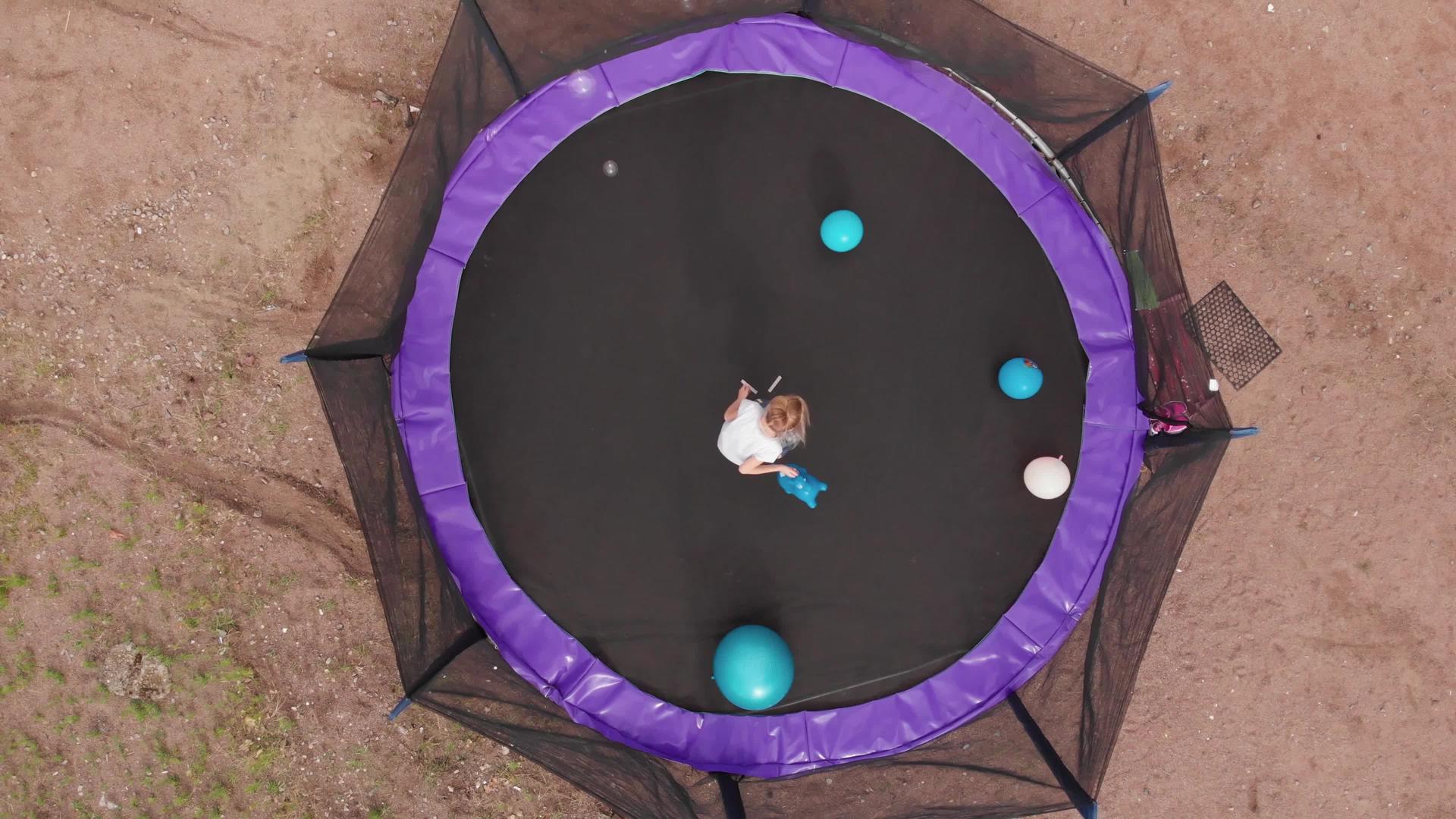 金发金发女孩在蹦床上跳跃玩乐球泡泡会从顶部飞来视频的预览图