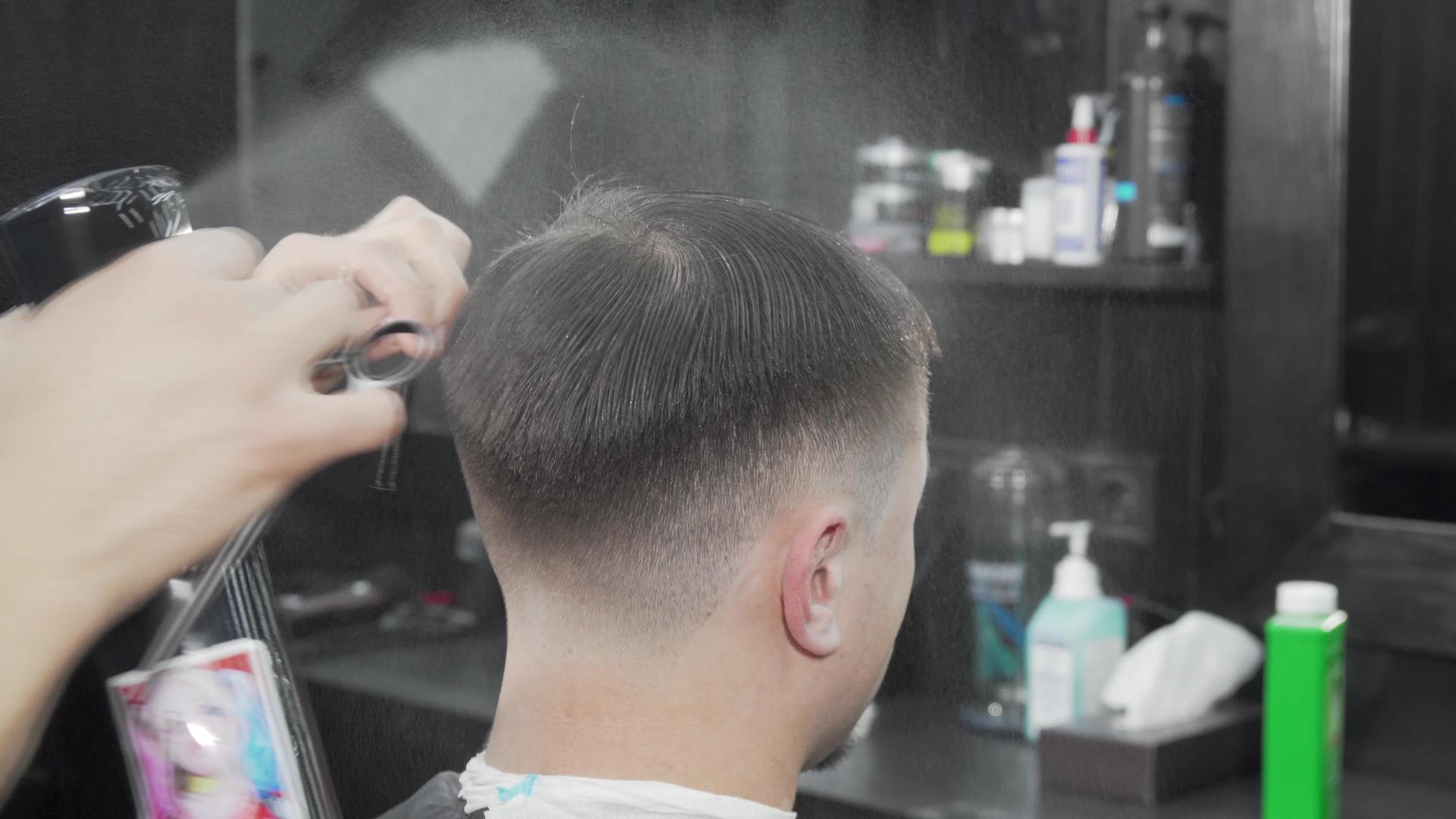 一位男性客户的专业理发师润湿并梳理头发视频的预览图
