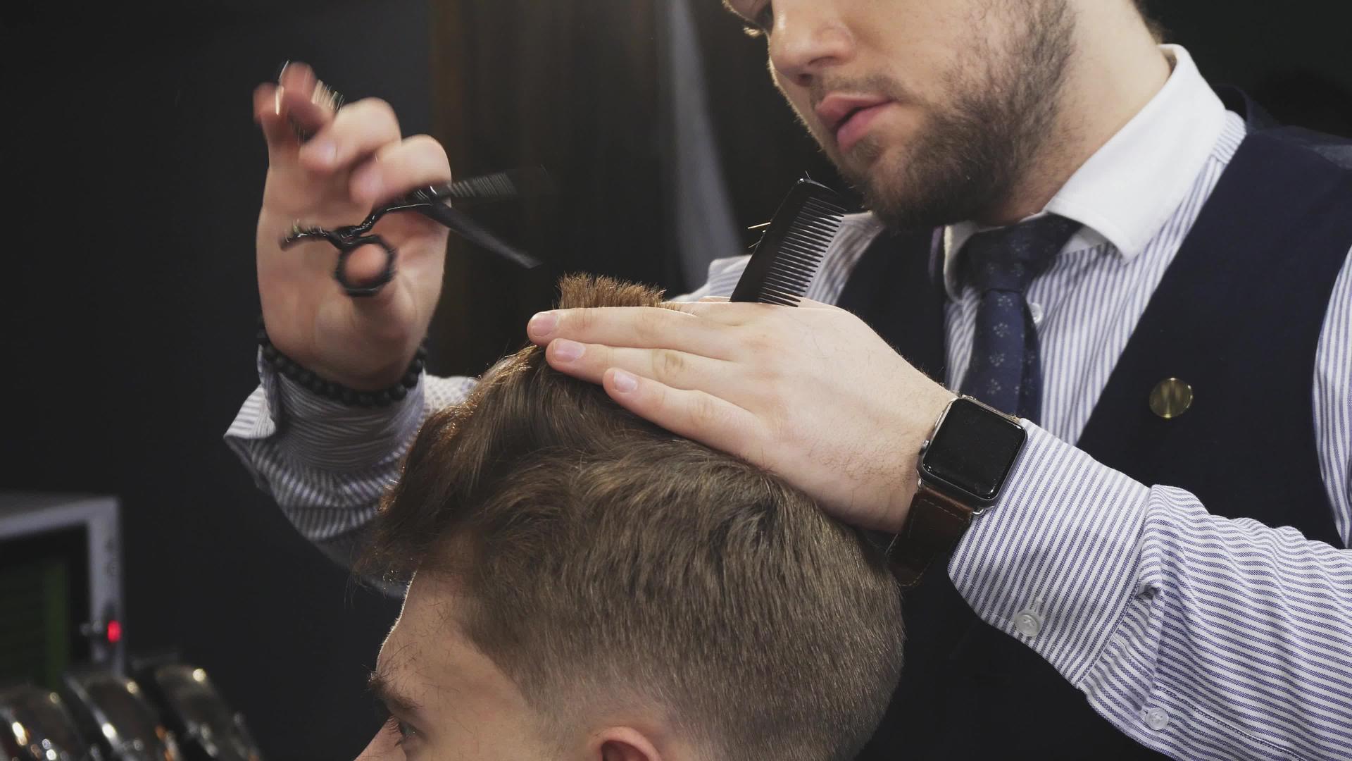 一位专业理发师为他的男性顾客剪头发视频的预览图