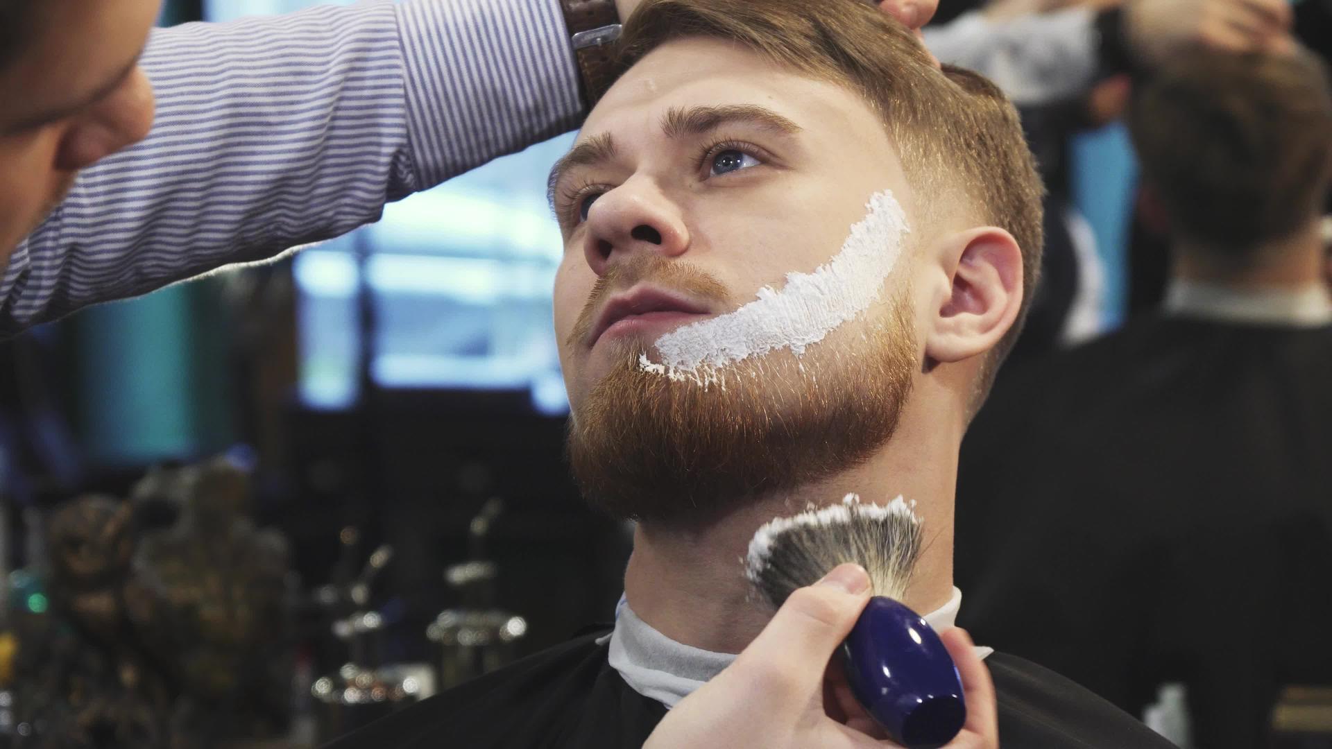 理发师在顾客的胡须上涂抹剃须膏视频的预览图