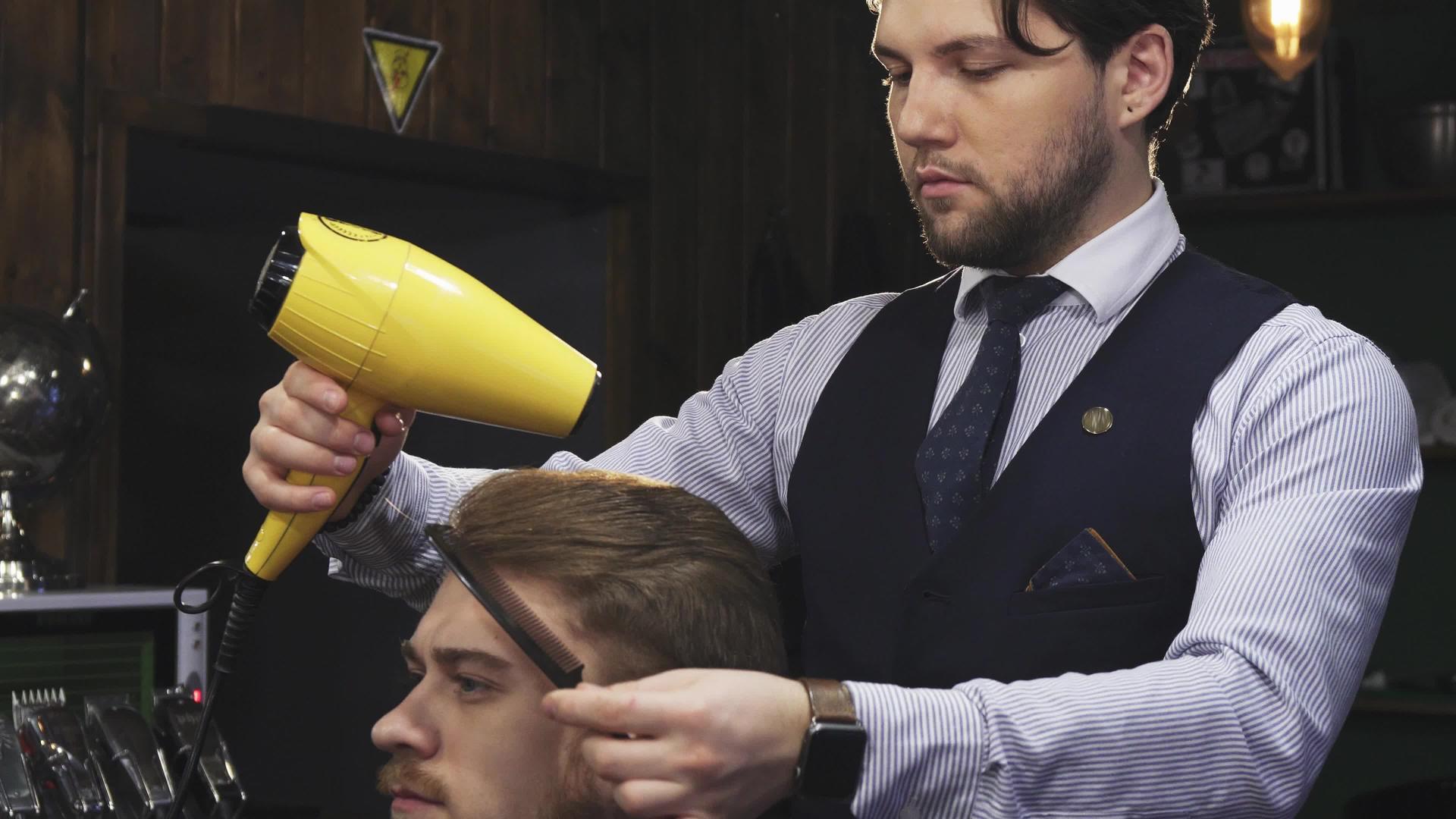 英俊的年轻男子的头发被理发师擦干了视频的预览图