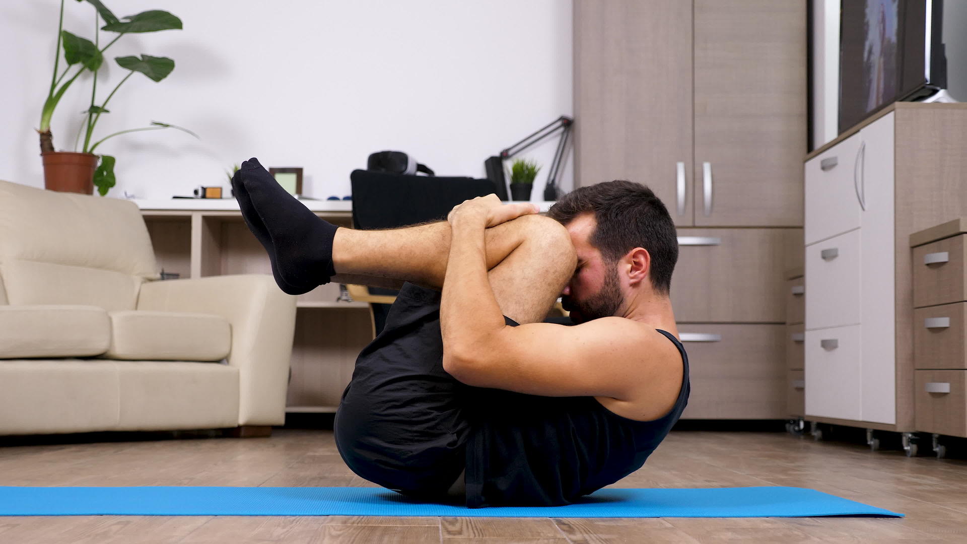 坐在客厅地板上的年轻健身男做不同的瑜伽姿势视频的预览图