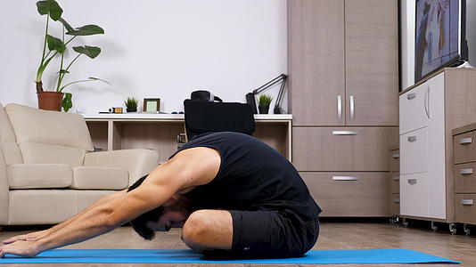 男人在家里的蓝色垫子上做不同的瑜伽姿势视频的预览图