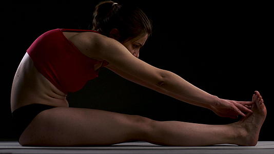 练习瑜伽的女孩伸展手臂和腿抚摸脚视频的预览图