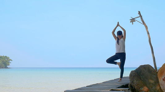 4K暑假期间一名妇女站在海上的木桥上练习瑜伽视频的预览图