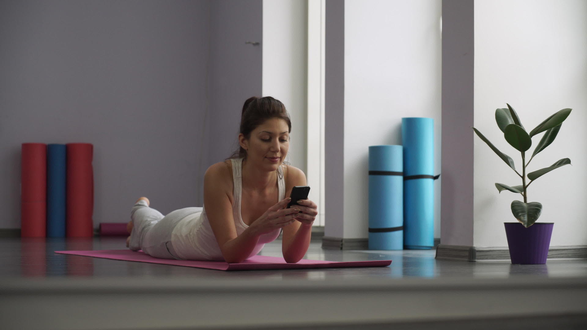 女人躺在瑜伽垫上看着电话视频的预览图