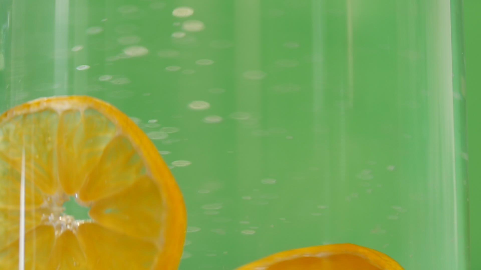 克莱门汀在玻璃水中飞溅绿色背景干净有机水果清新实现视频的预览图