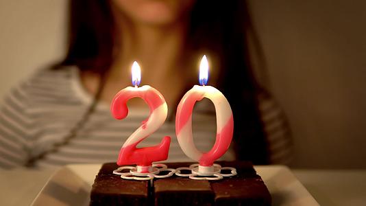 庆祝她20岁生日年轻女孩在室内烤蛋糕上吹蜡烛视频的预览图