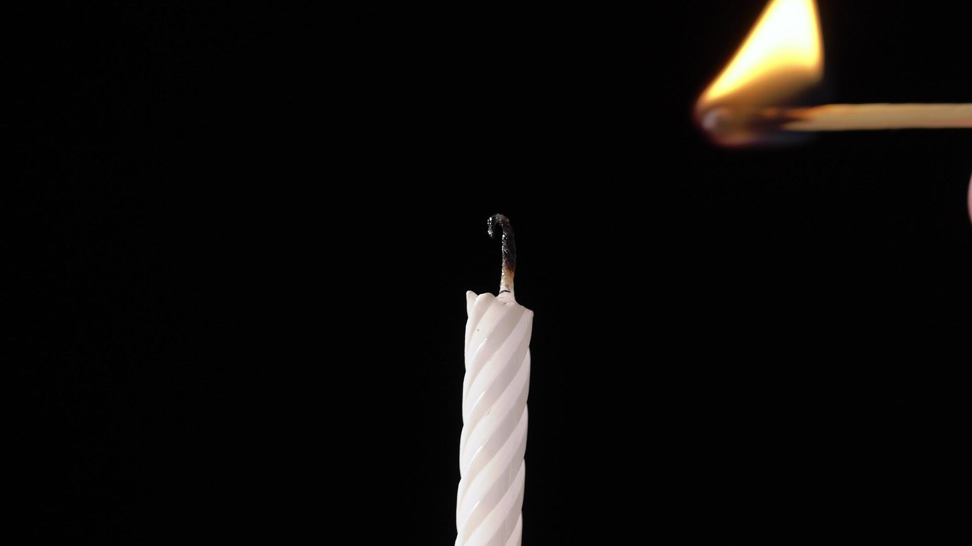 在庆祝生日蛋糕时用黑色背景点燃蜡烛视频的预览图