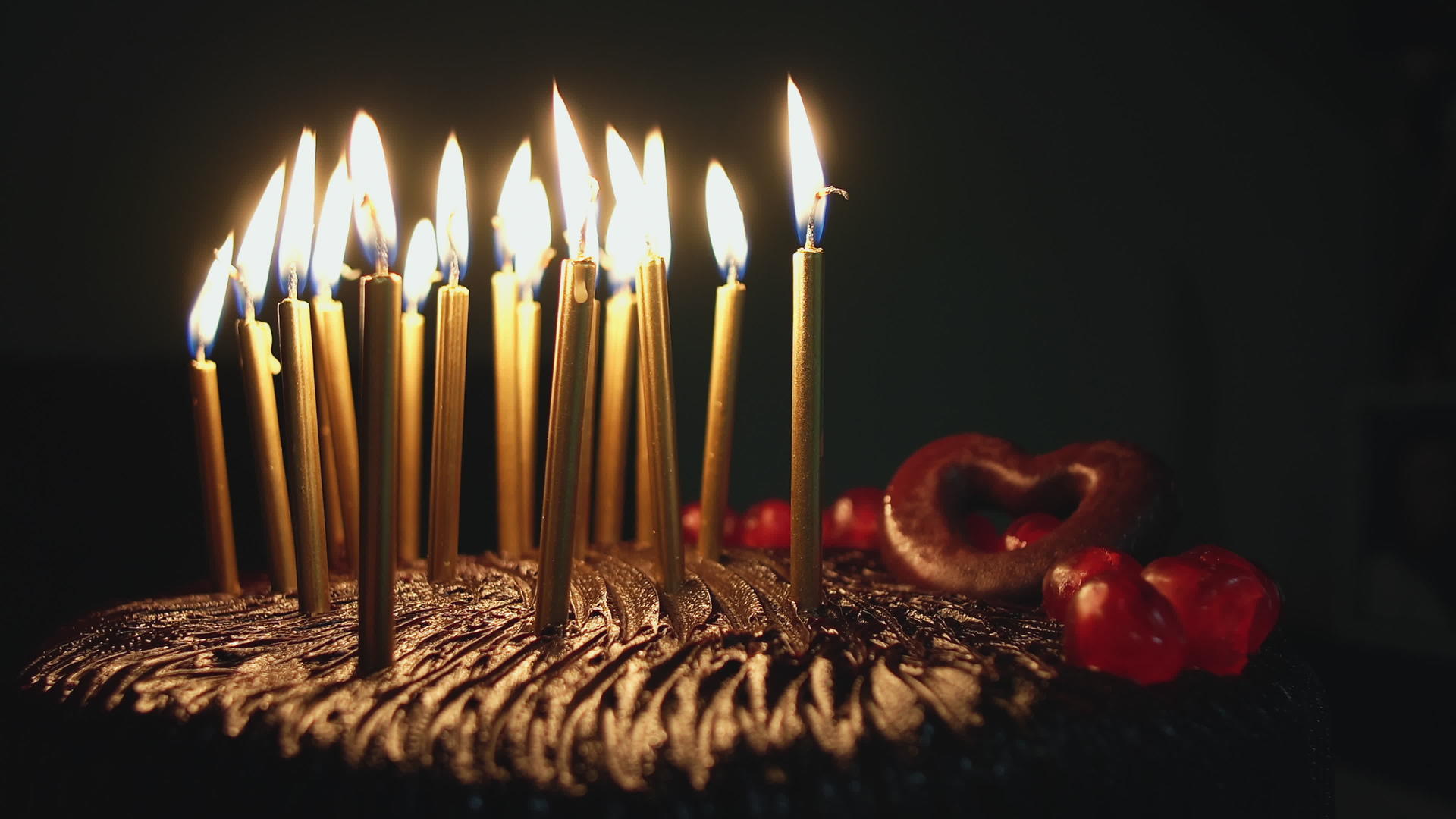 生日快乐巧克力蛋糕和彩色金蜡烛在黑暗中闪耀视频的预览图