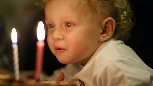 小男孩在生日蛋糕上吹了两根蜡烛视频的预览图