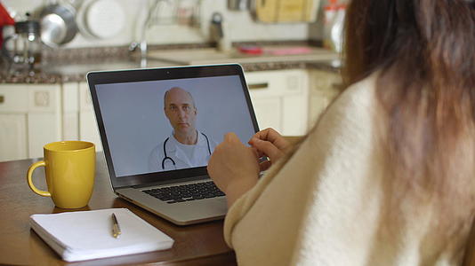 生病的妇女在家里的笔记本电脑屏幕上进行视频通话视频的预览图