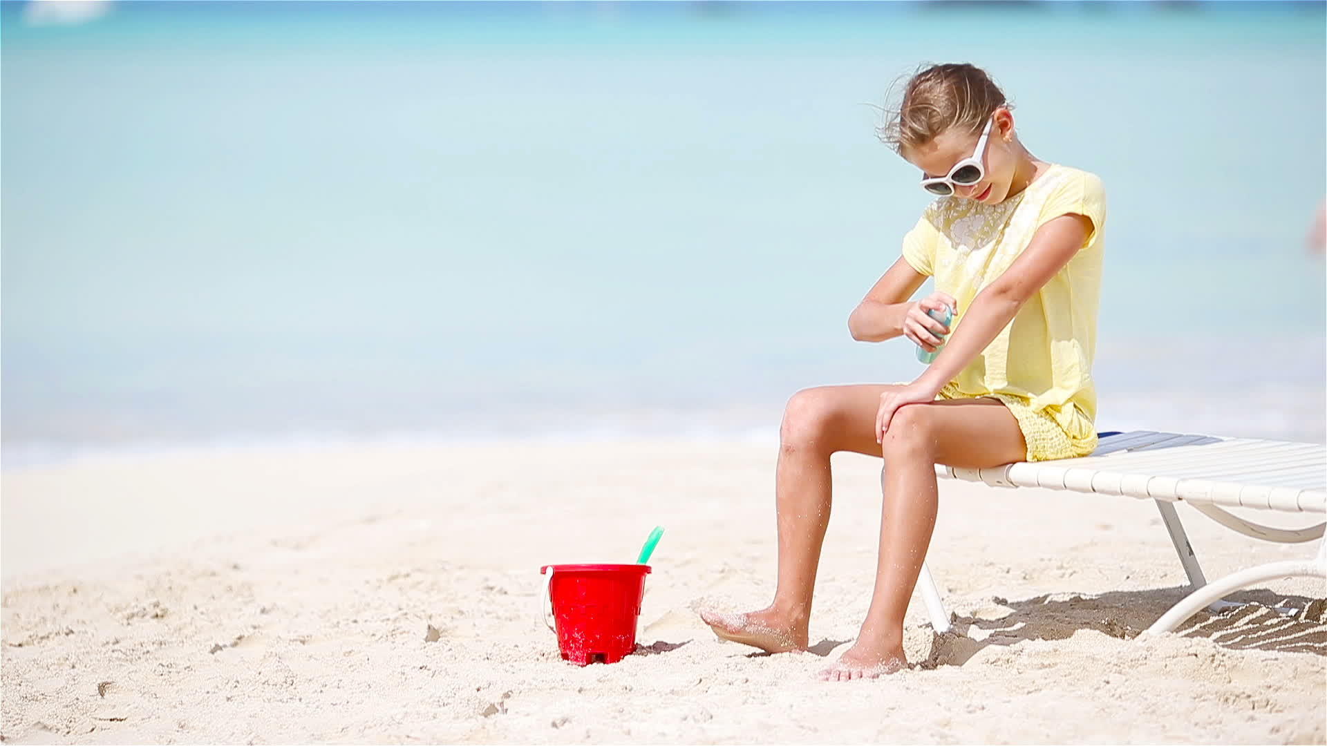 戴着帽子的小女孩坐在热带海滩上视频的预览图