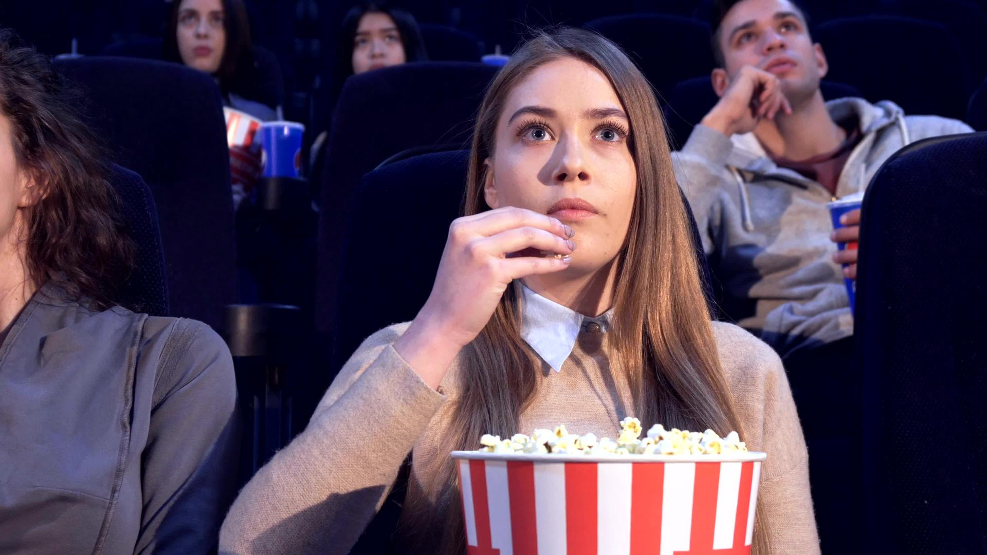 女孩慢慢地把爆米花放进嘴里在电影院里视频的预览图