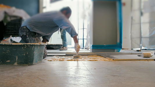把阴铁瓷砖放在地板上的工人电影视频的预览图