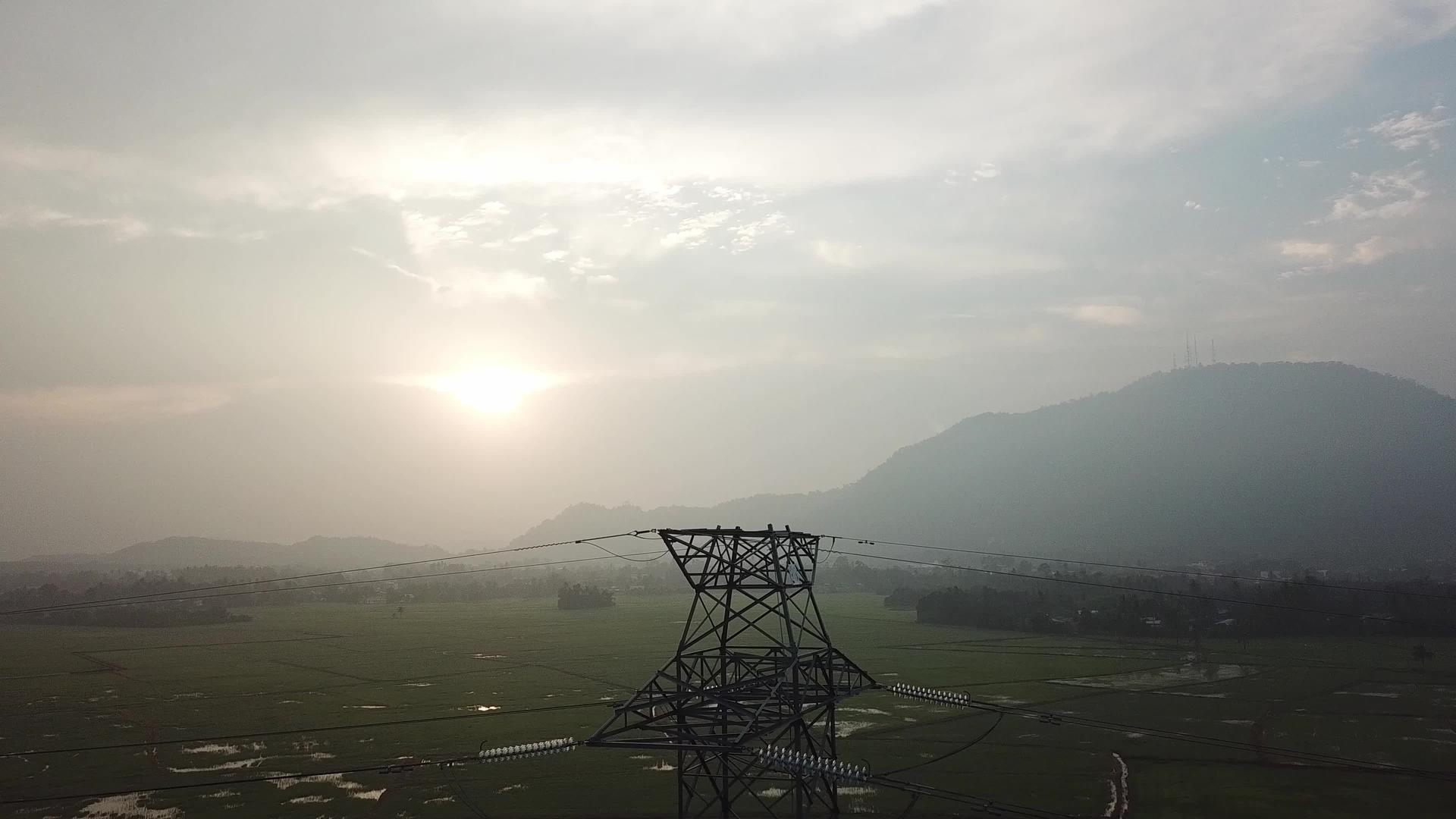 在稻田中用背景山丘观察空中电塔的水稻田视频的预览图