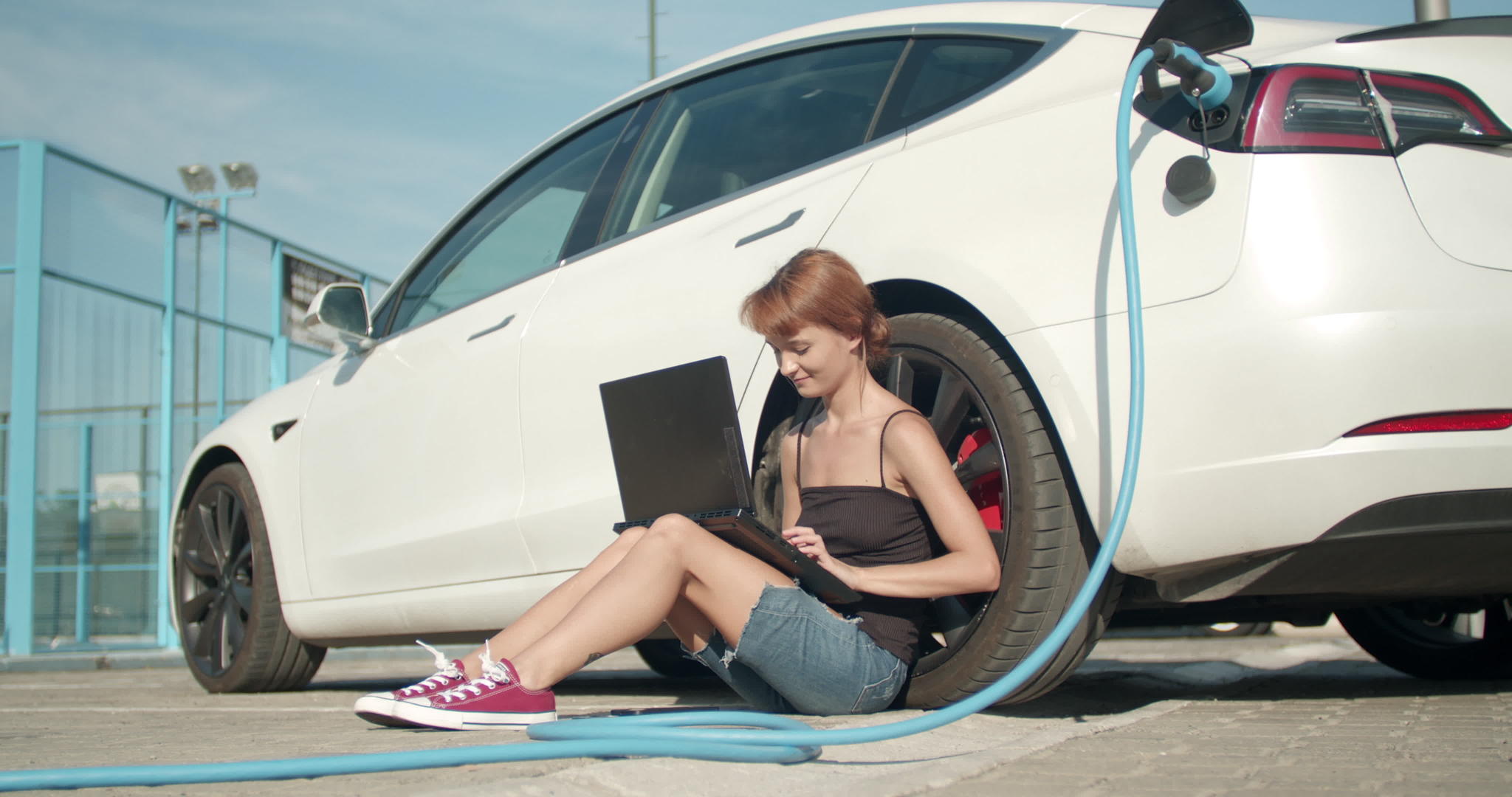 电动车充电时女孩在地上等着在笔记本电脑上工作视频的预览图