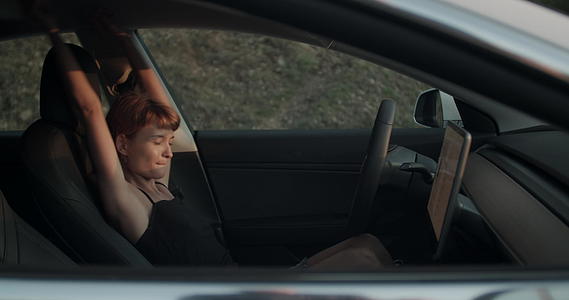 坐在司机的座位上听音乐和跳舞的手持视频在她的电动车里视频的预览图