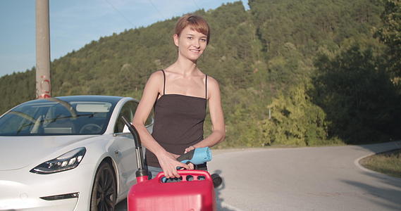 靠近电动汽车的女孩有充电电缆和汽油罐搭便车视频的预览图