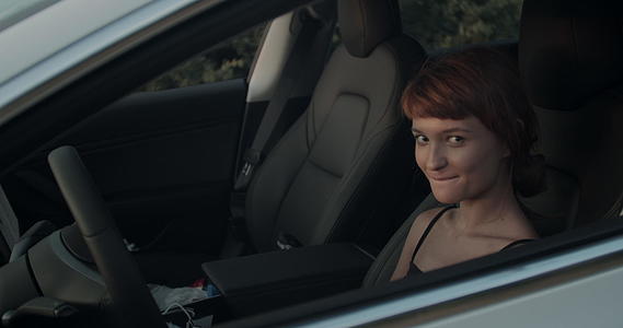 在电动汽车上切开女孩透过窗户看手持视频视频的预览图