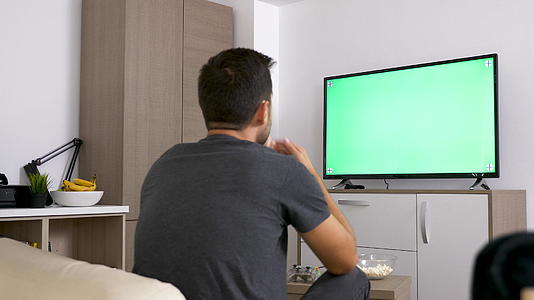 男人看大型绿色模拟屏幕电视视频的预览图