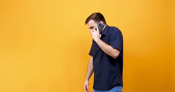 愤怒的年轻人穿着蓝色衬衫在电话里说话视频的预览图