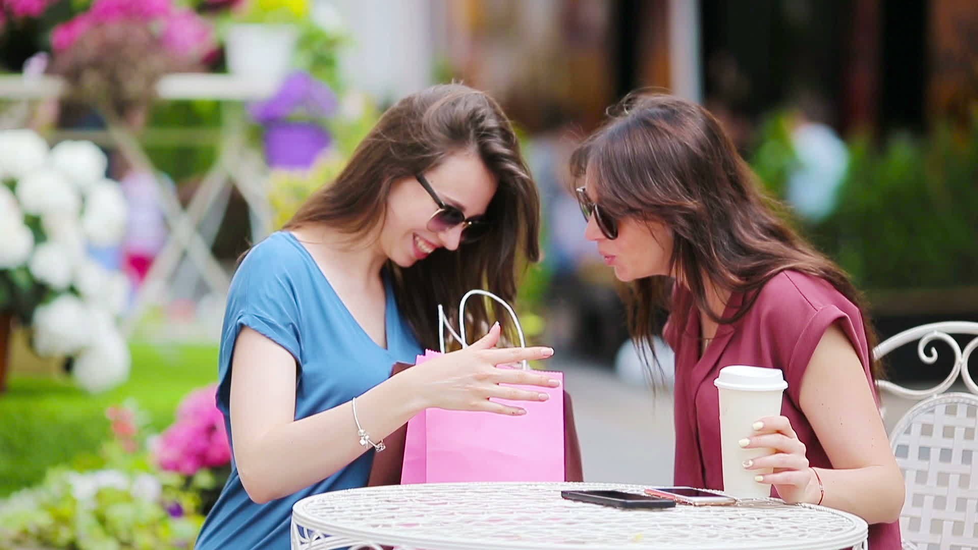 两个年轻女孩和两个女人在户外咖啡馆购物坐在袋子里视频的预览图