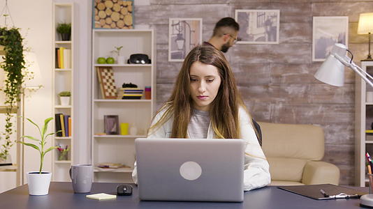 年轻漂亮的年轻女性在家庭办公室用笔记本电脑工作视频的预览图