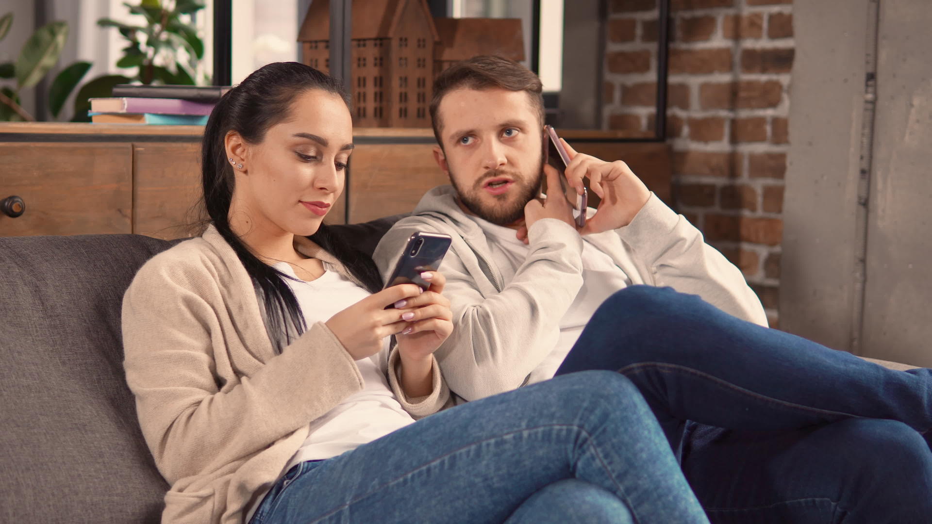 懒惰的夫妇坐在沙发上用手机视频的预览图