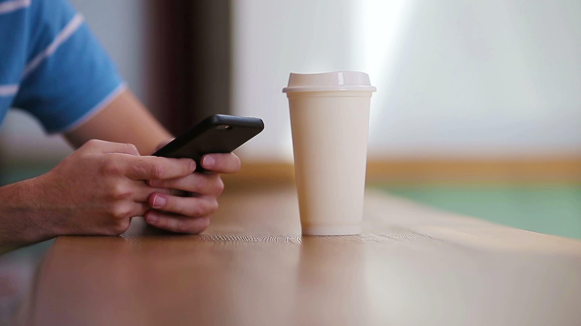 手持手机和一杯咖啡的男性手在咖啡馆的特写使用视频的预览图