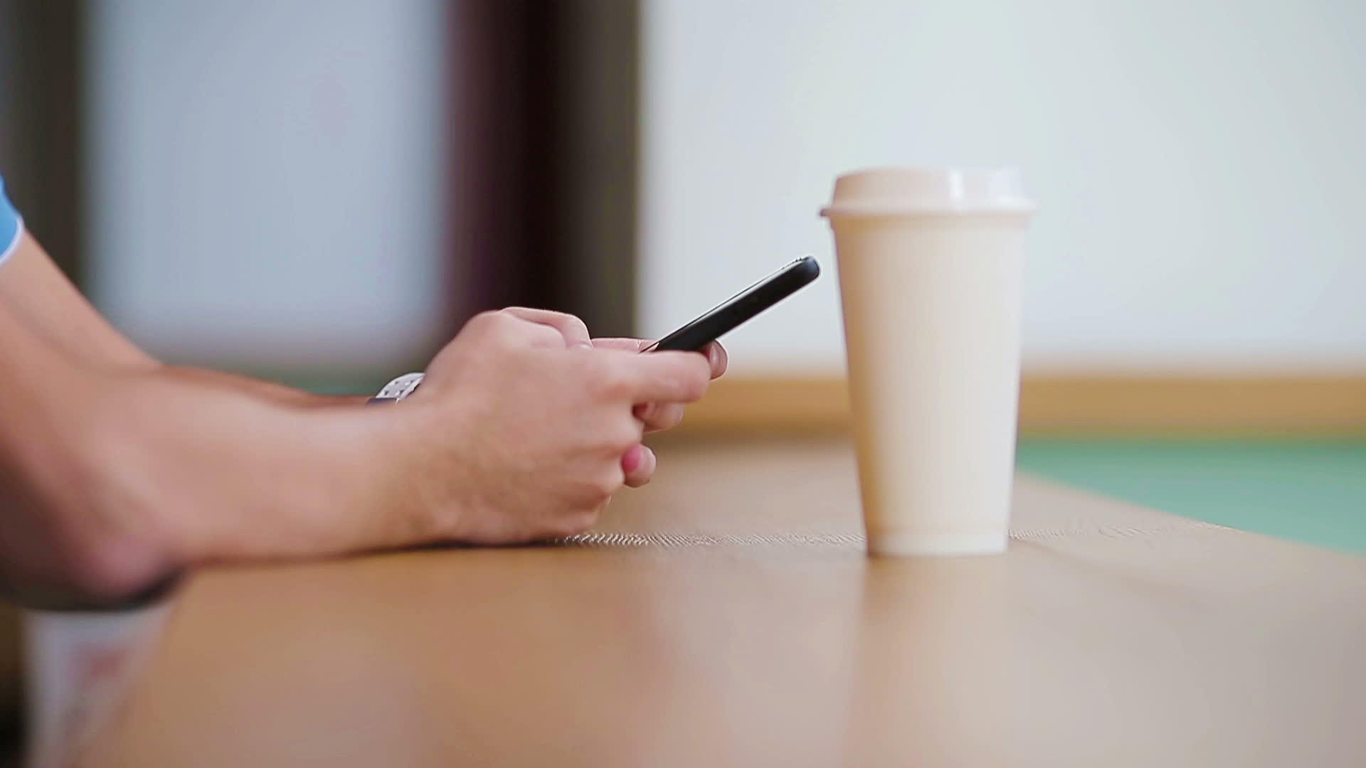 手持手机和一杯咖啡的男性手在咖啡馆的特写使用视频的预览图