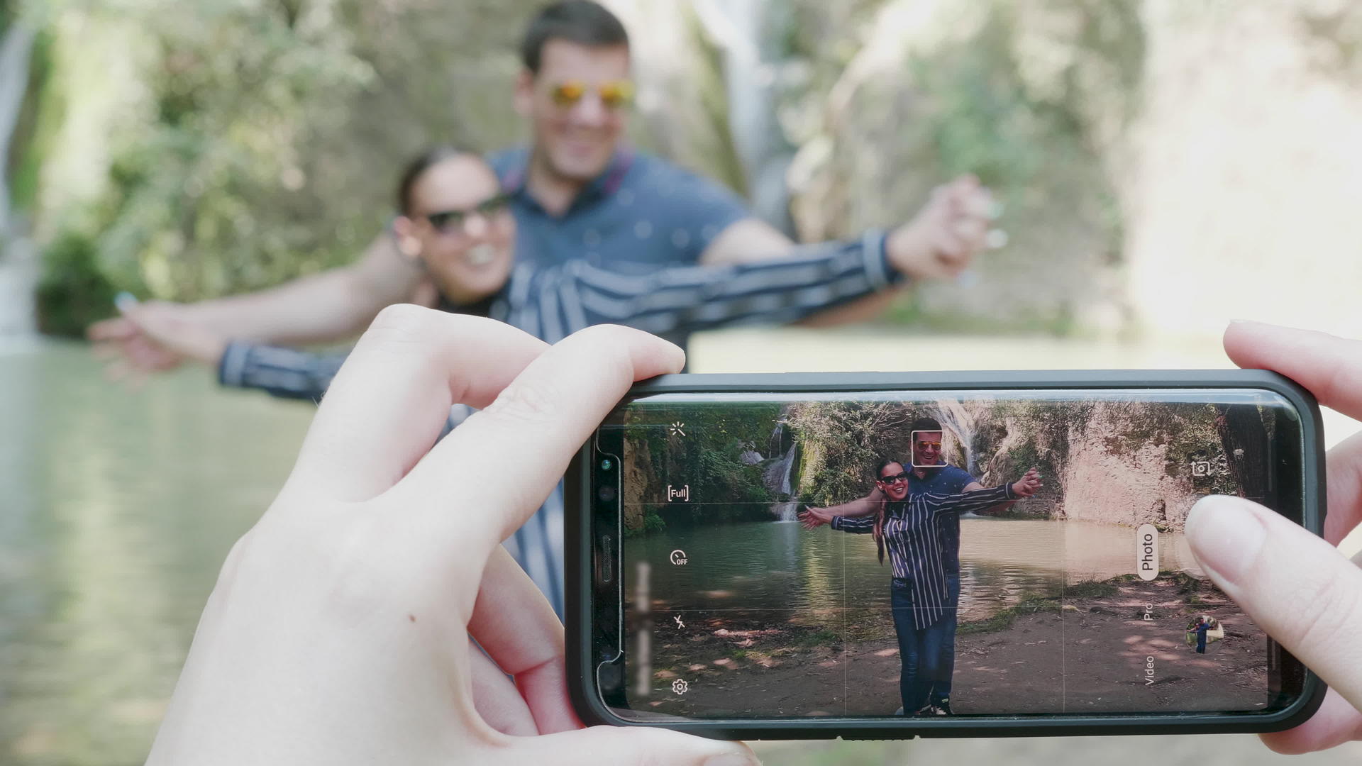在瀑布附近用手机拍情侣照片视频的预览图
