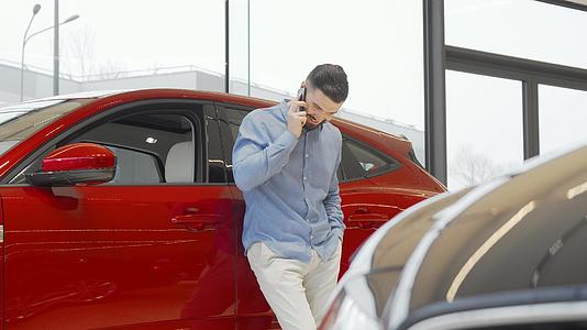 迷人的男人用智能电话说话在经销商中选择新车视频的预览图