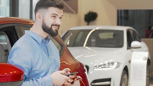 快乐的男人在商场买新车时在智能手机上发短信视频的预览图