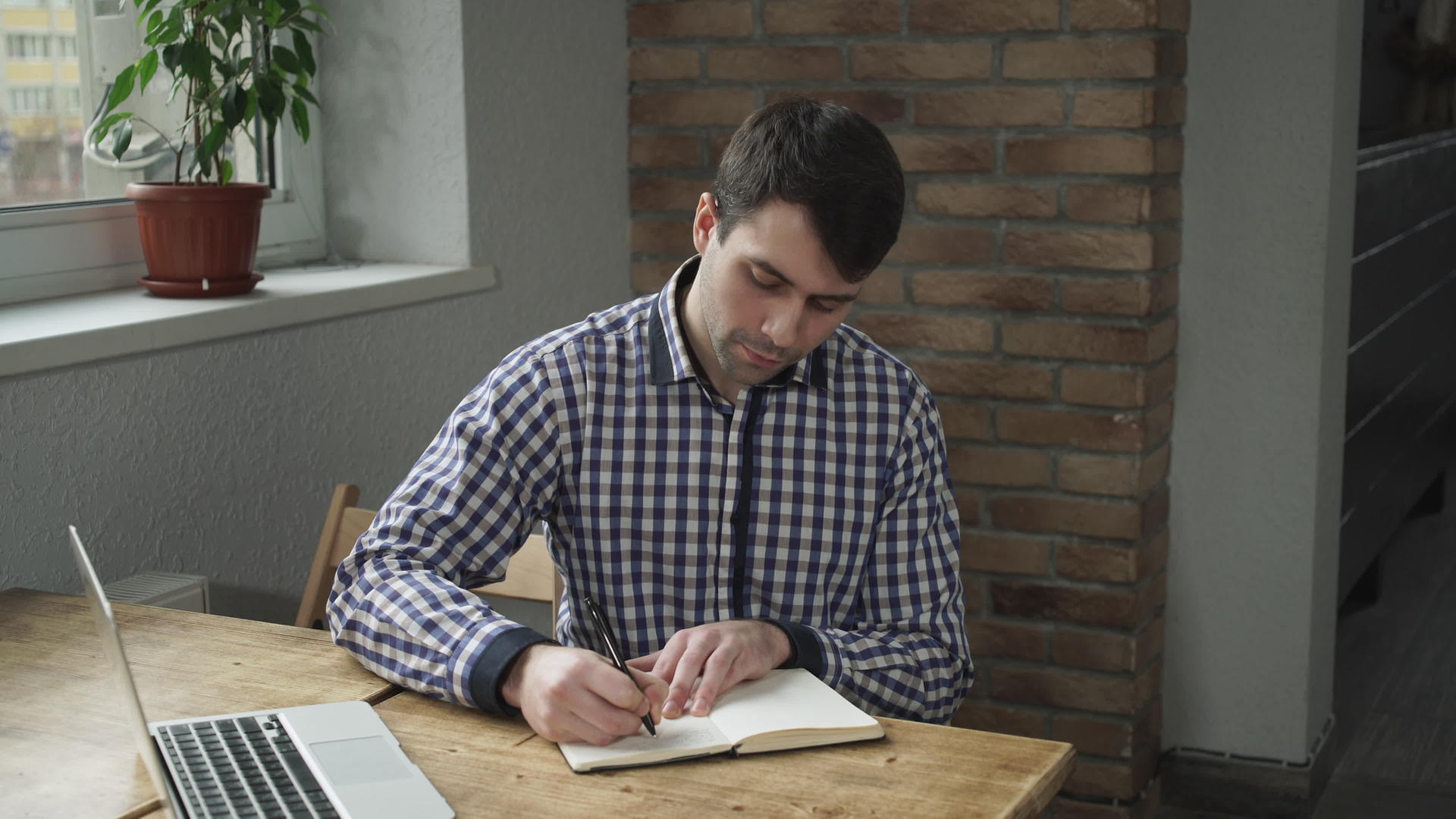 穿衬衫的男人在日记里做笔记看着笔记本电脑视频的预览图