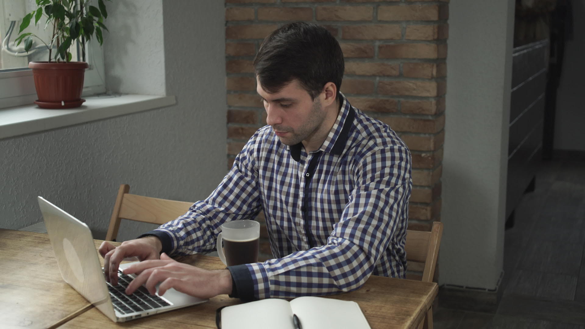 一名穿着格子衬衫的男子盯着监视器喝了一小口咖啡视频的预览图