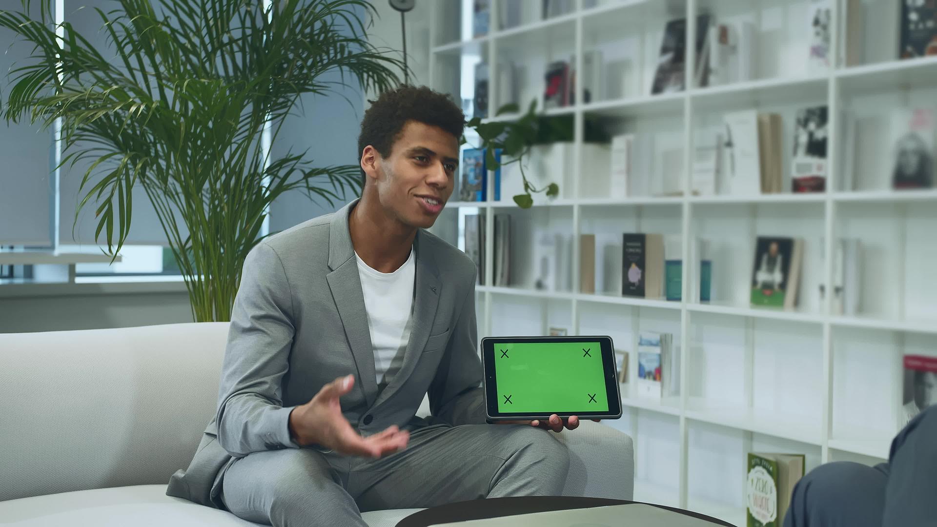 黑色正式男子使用带有绿色关键屏幕的平板电脑进行演示视频的预览图