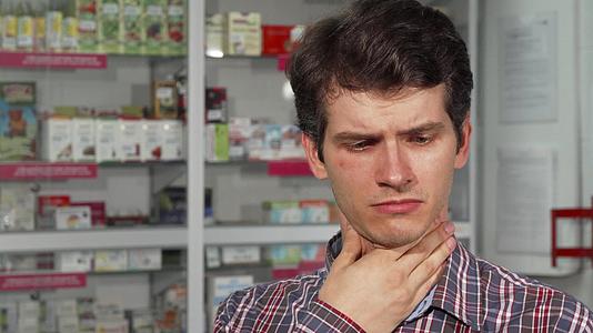英俊的年轻人咳嗽喉咙痛站在药店里视频的预览图