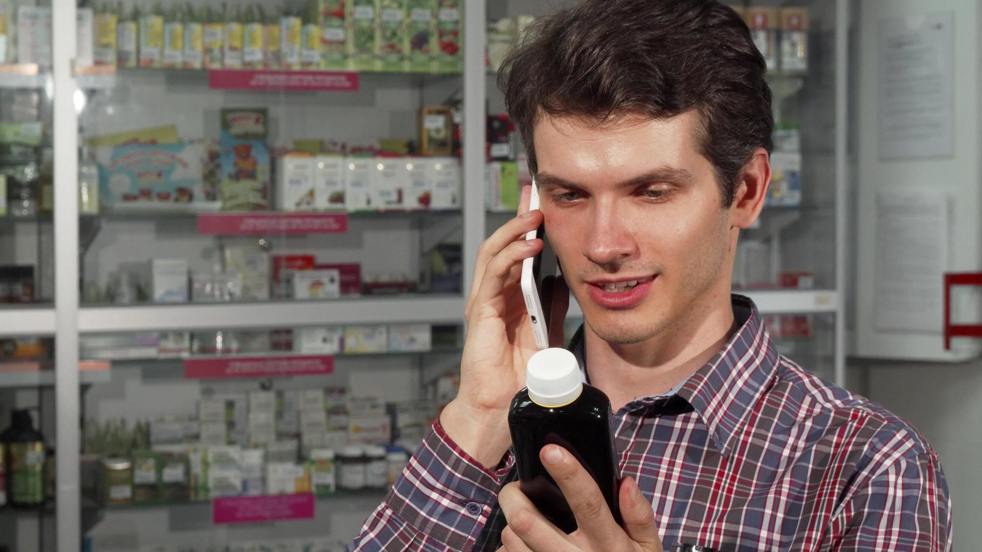 年轻男子在药店购物时使用智能手机视频的预览图
