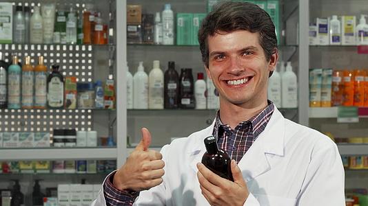快乐的药剂师在药店工作时举起拇指视频的预览图