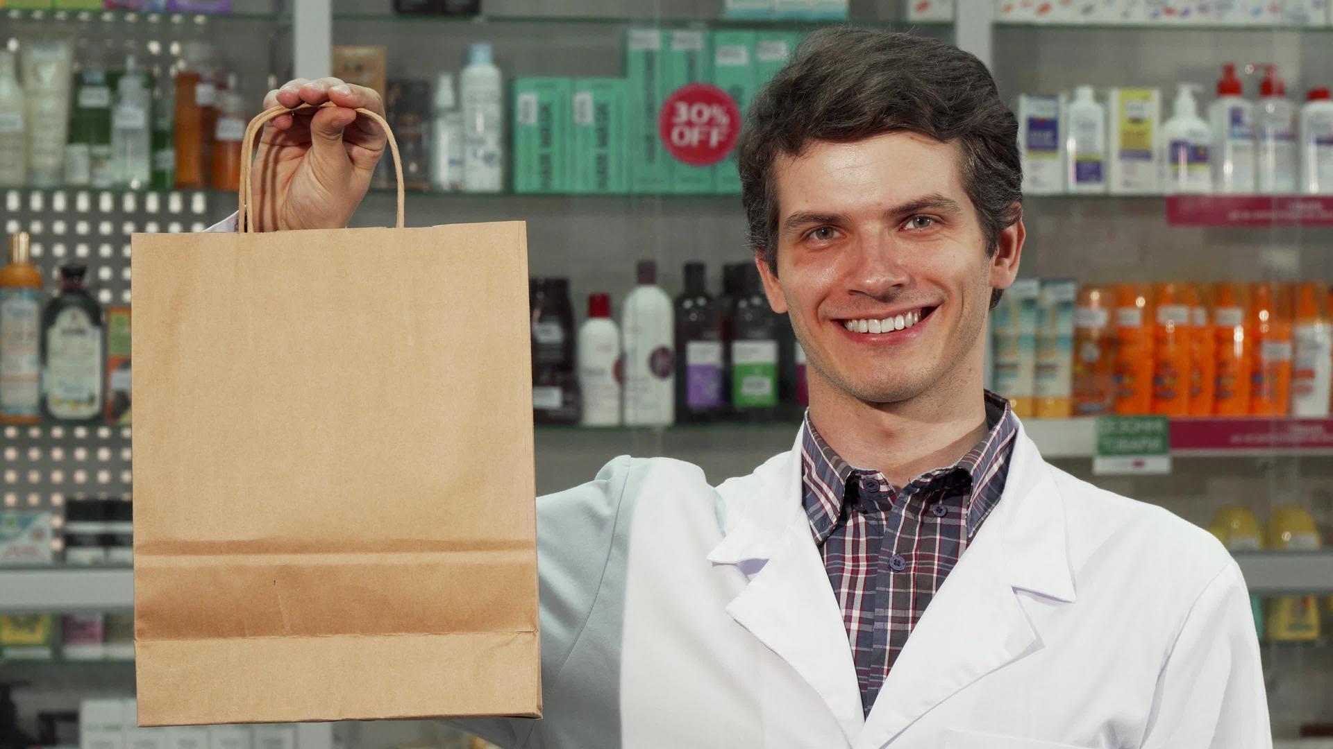 快乐的药剂师拿着购物袋对着相机微笑视频的预览图