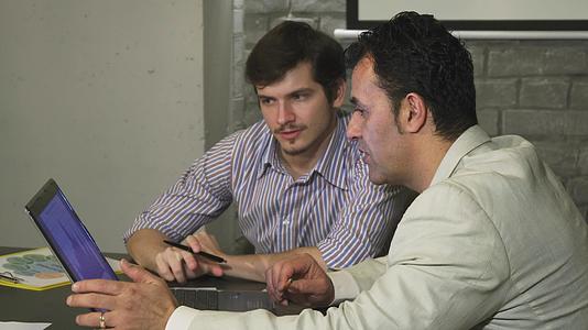 英俊的商人用笔记本电脑和老板见面视频的预览图