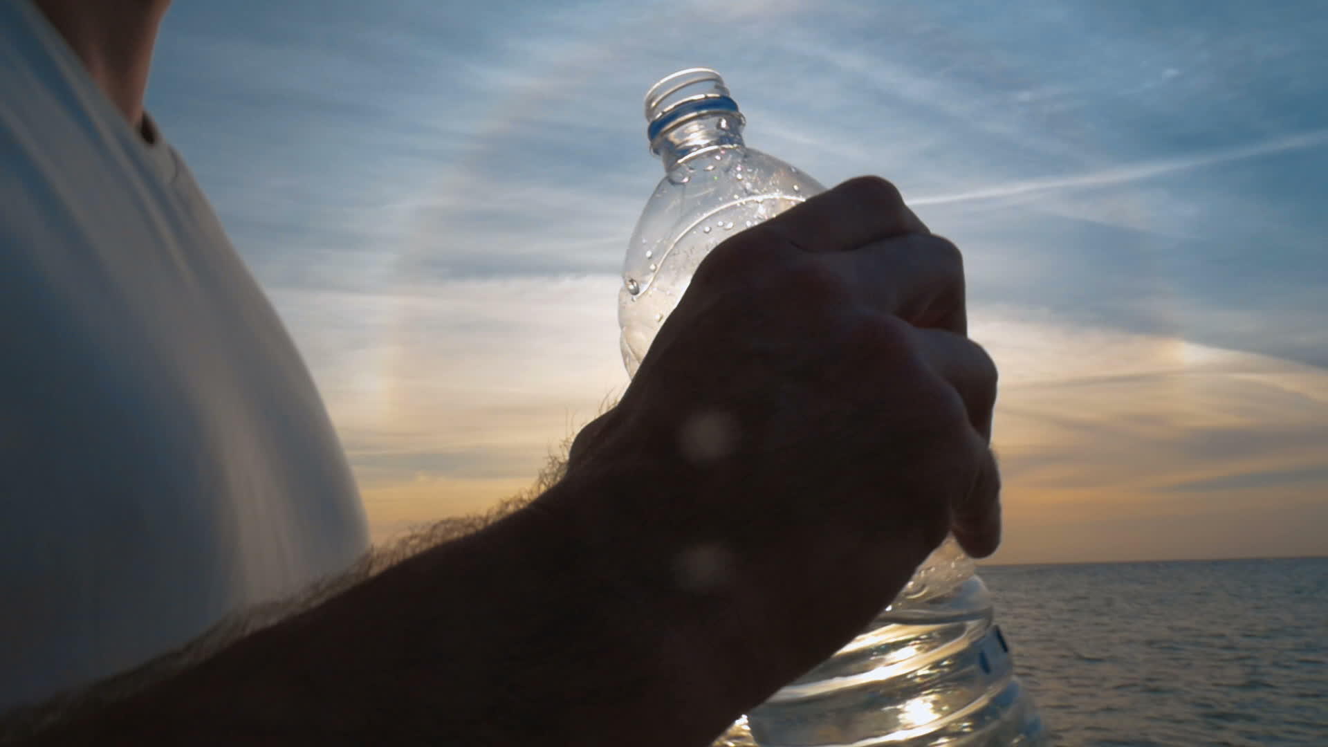 日落时男人从瓶子里喝水视频的预览图