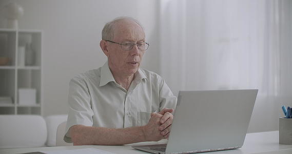 老人正在用带有互联网的笔记本电脑和专家呆在家里视频的预览图